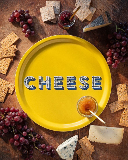 Asta Barrington Yellow "Cheese" Round Tray (31cm) with grapes, crackers, and cheese on a wooden table.
