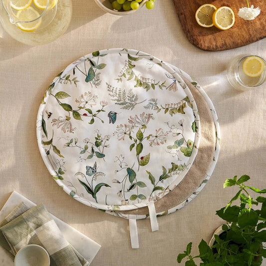 Sophie Allport "Wild Floral" Chefs Pad For Use With Aga Range Cookers on a dining table with fruits and herbs.