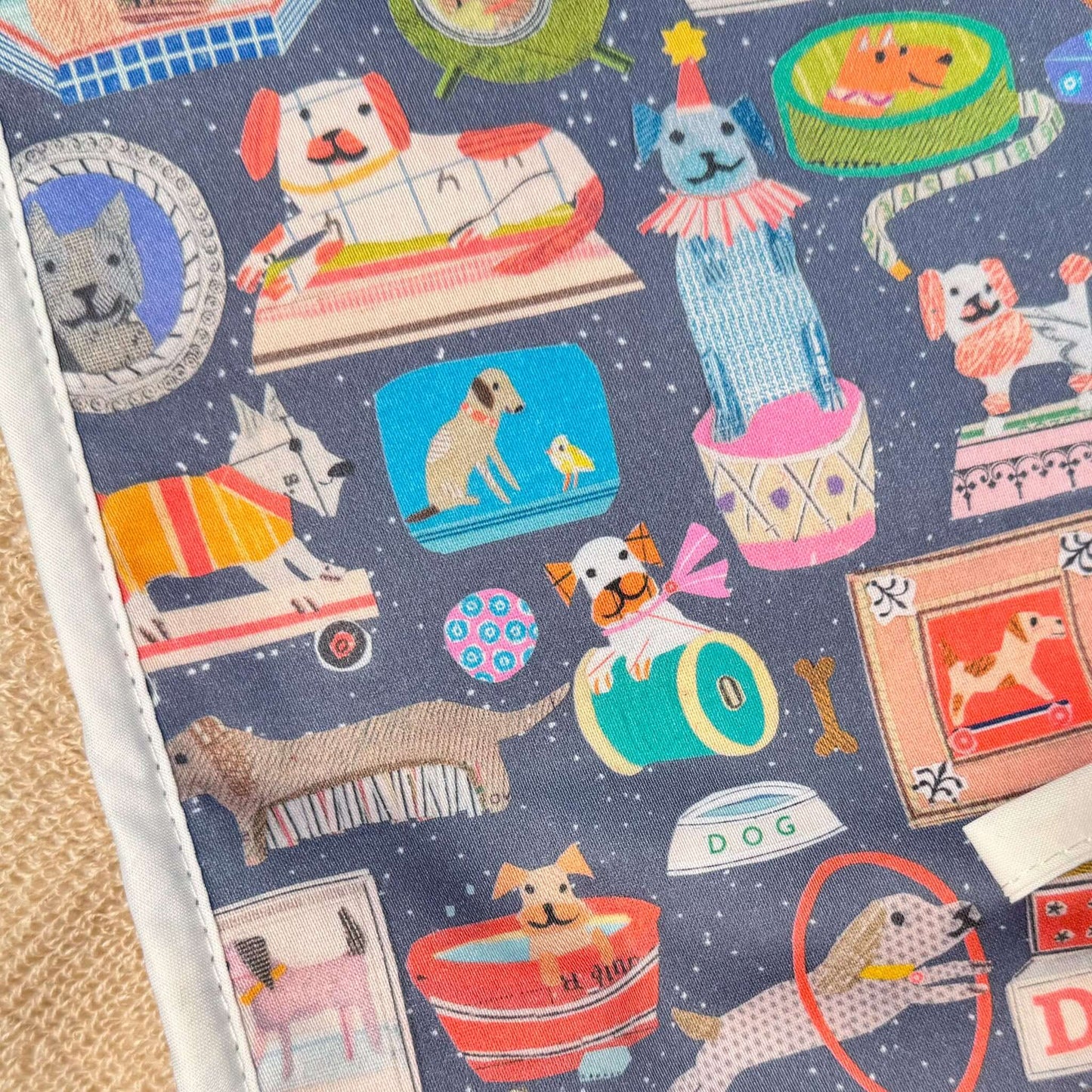 Colorful fabric pattern featuring playful dogs in various activities on a double oven glove.