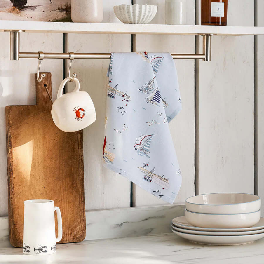 Sophie Allport "Coastal Boats" Tea Towel hanging in a kitchen with nautical boat print on a pale blue background.