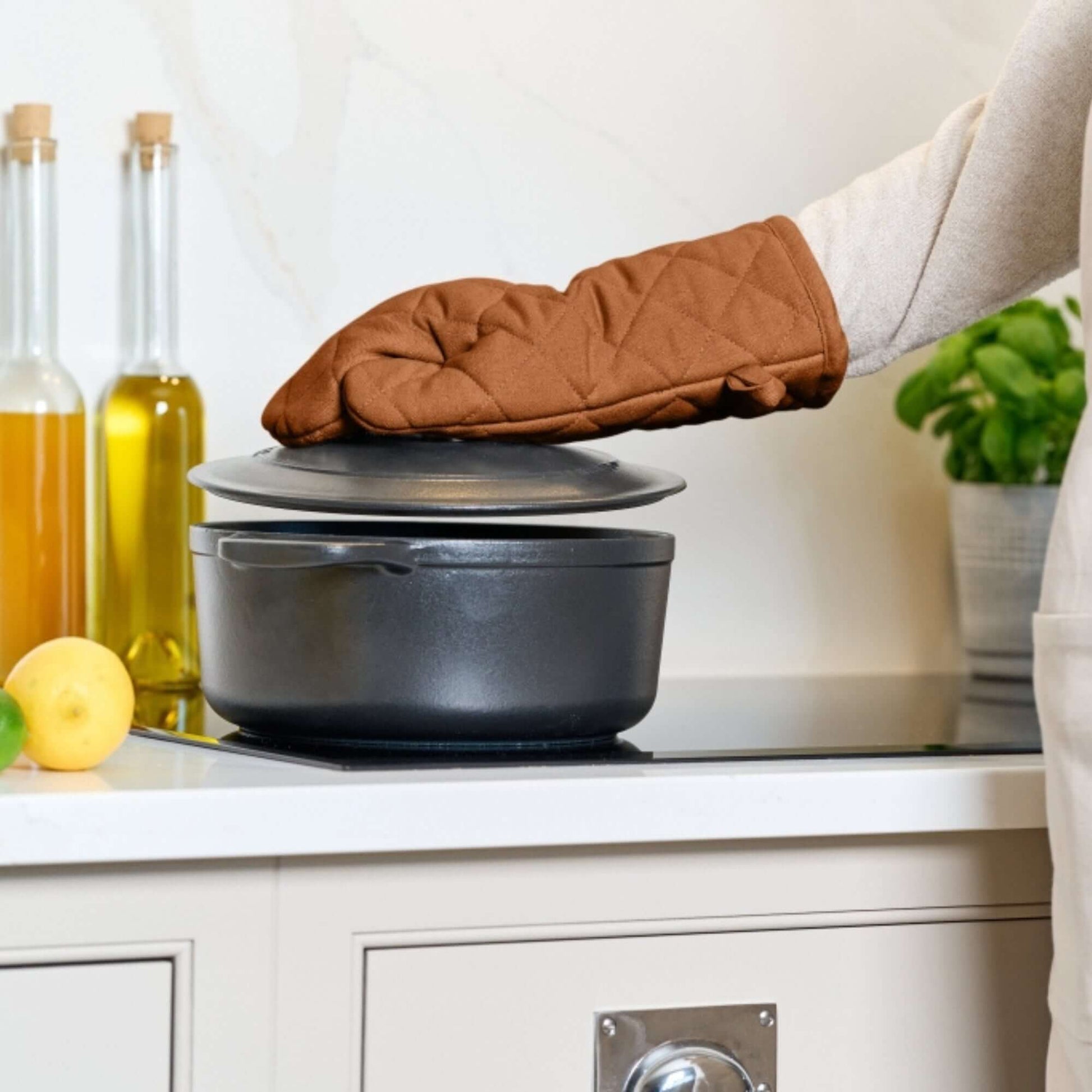 Oven Gauntlet - Dexam - Love Colour - Terracotta used to handle a pot in a kitchen setting with olive oil and fresh lemons.